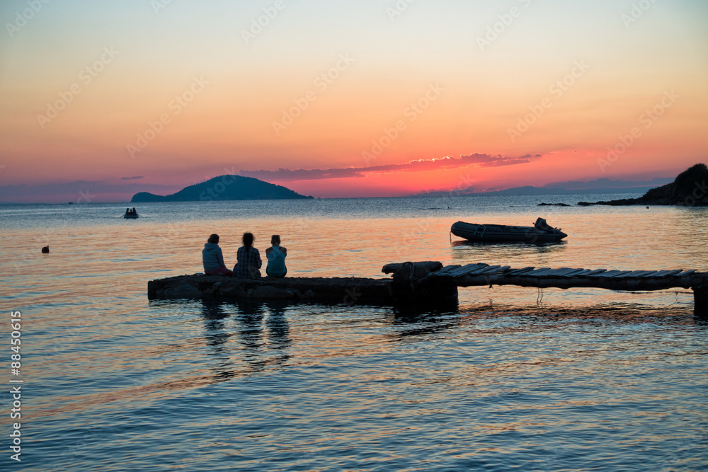 Girls sitting on a pier at sunset in Sithonia