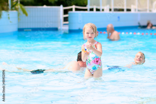 Happy family having fun in recreation swimming pool. Children enjoying day in waterpark during active summer holidays. Kids laughing and playing with waterguns.