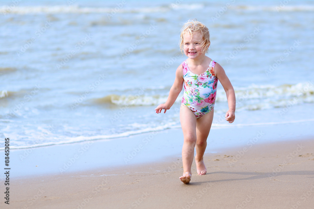 Cute active child playing on sandy beach. Happy little girl enjoying summer holidays on a sunny day. Family with young kids on vacation at the North Sea coast. Cute active child playing on sandy beach. Happy little girl enjoying summer holidays on a sunny day. Family with young kids on vacation at the North Sea coast.