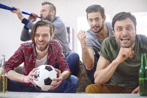 Football fans watching match at home