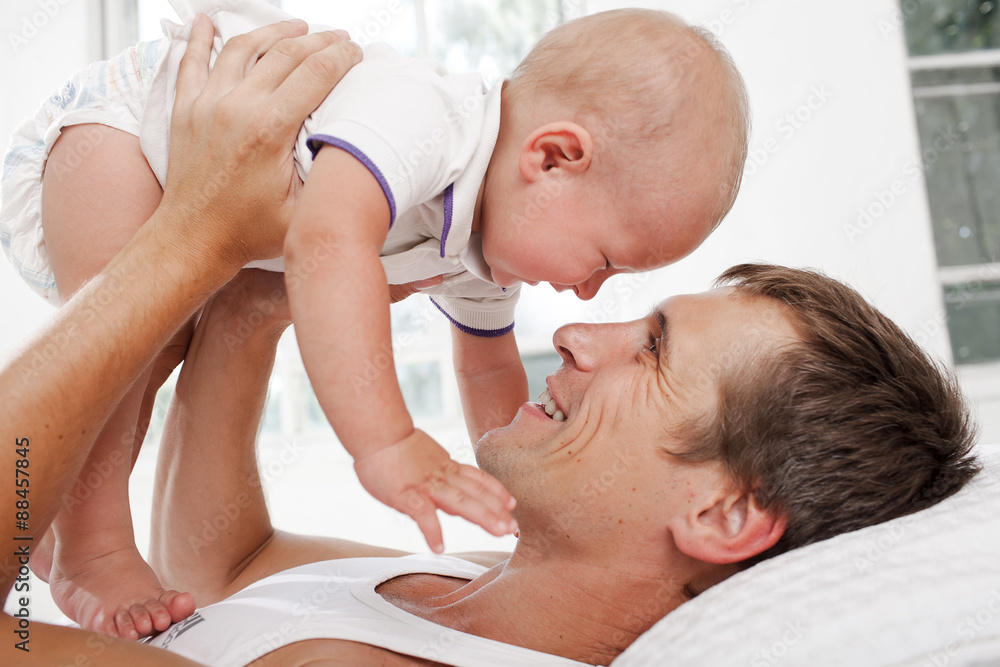 Fototapeta premium young father with his nine months old son on the bed at home