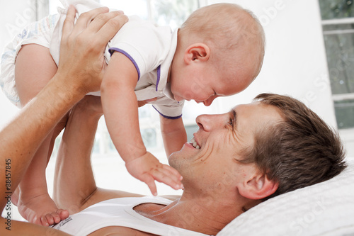 young father with his nine months old son on the bed at home