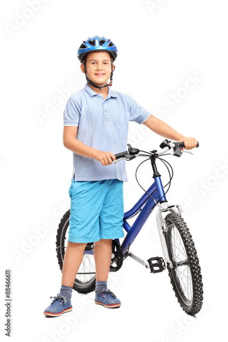 Little kid with blue helmet posing next to his bicycle