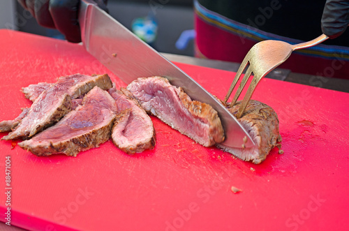 Chef slicing grilled meat medium rare