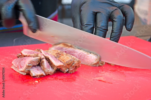 Chef slicing grilled meat medium rare