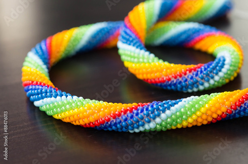 Wallpaper Mural Necklace rainbow colors on dark wooden surface close-up Torontodigital.ca