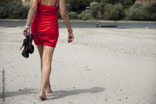 Woman in red dress barefoot stroll on the beach