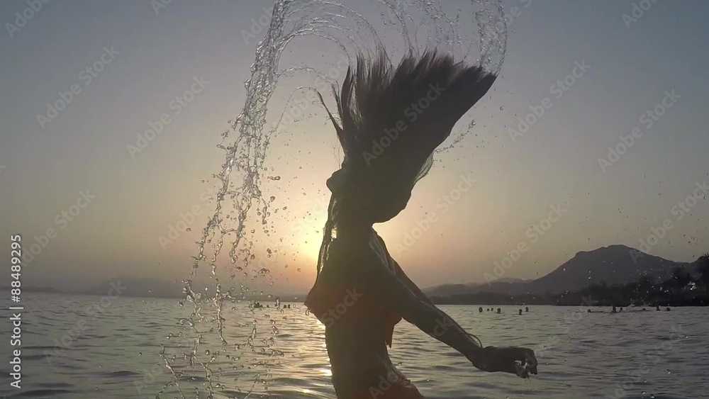 CHICA SALIENDO DEL MAR SALTANDO Y SALPICANDO CON SU PELO: grabado a cámara lenta a 120fps camara en mano