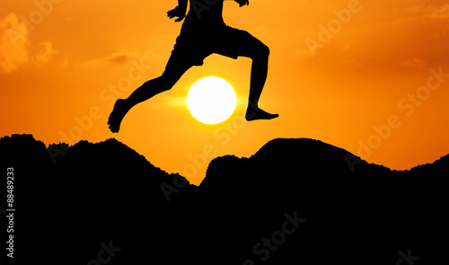 silhouette of theyoung man jumpping at mountain yellow sunset ba photo