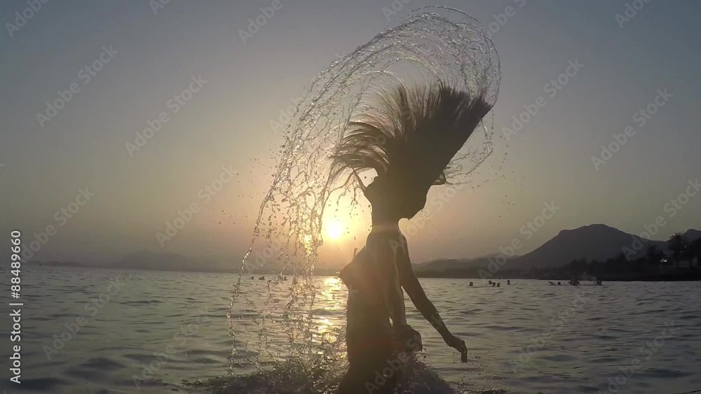 CHICA SALIENDO DEL MAR SALTANDO Y SALPICANDO CON SU PELO: grabado a cámara lenta a 120fps camara en mano