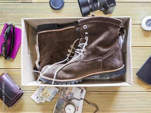 Open box with a pair of boots. Preparing an adventure trip.