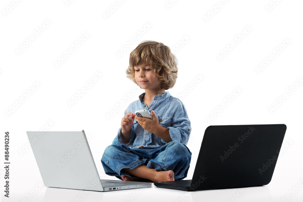 Little boy playing with a smart phote and two laptops Little boy playing with a smart phote and two laptops