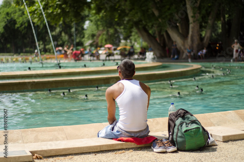 Young fit african man sitting backward near fountain