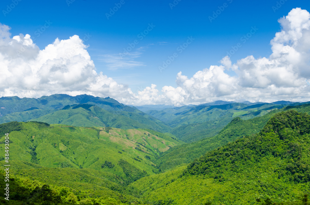 Naklejka premium green mountains and blue sky with clouds