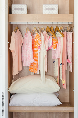 colorful kid's clothes hanging on bar in wooden wardrobe © 290712