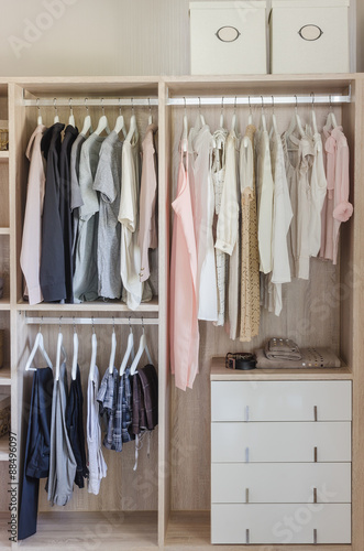 clothes hanging in wooden wardrobe