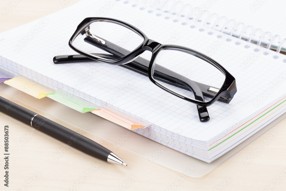 Office table with glasses over notepad Office table with glasses over notepad