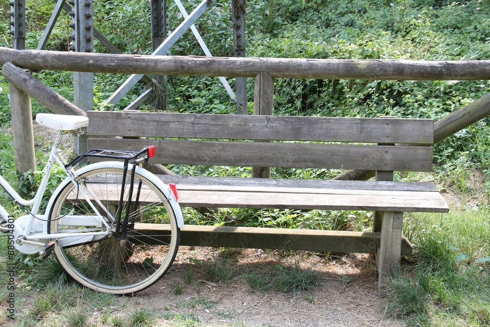 Bicycle leaning against a park bench Bicycle leaning against a park bench