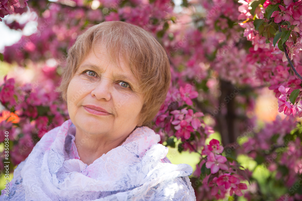 Fototapeta premium adult Russian woman under pink flowers in park