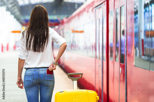 Young caucasian girl with luggage at station traveling by train