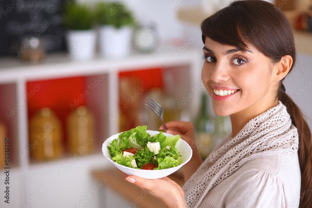 Young woman eating fresh salad in modern kitchen Young woman eating fresh salad in modern kitchen