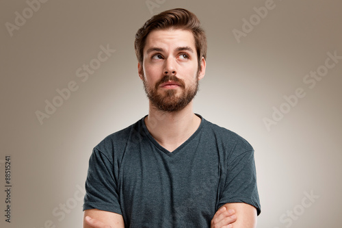 Portrait of young man with beard, looking up photo