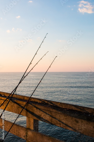 Fishing poles resting on piers with ocean background and clouds. 