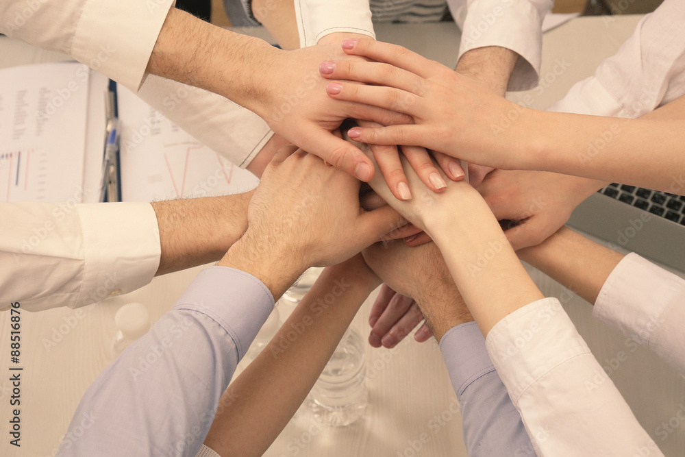 United hands of business team on workspace background top view United hands of business team on workspace background top view