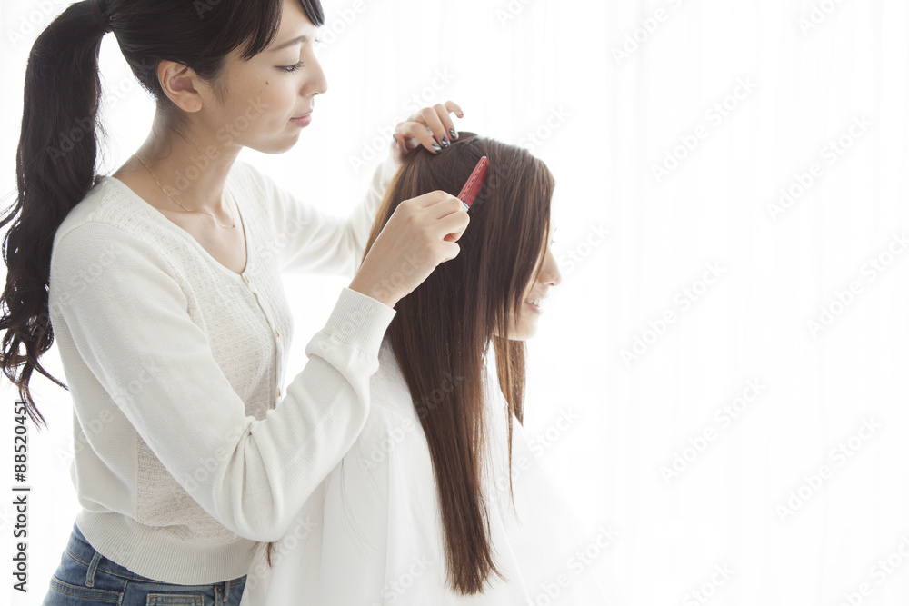 Fototapeta premium Hairdresser is dissolved a woman's hair with comb