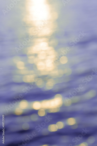 Abstract golden sunlight bokeh on blue sea water background.