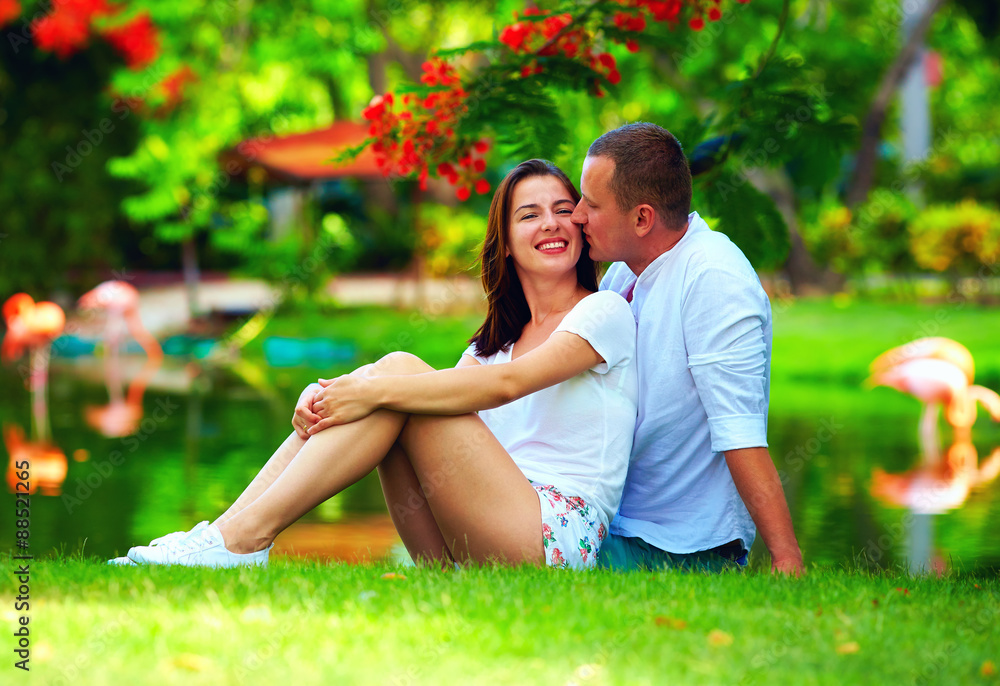 Fototapeta premium happy young couple in love sitting near pond with flamingo