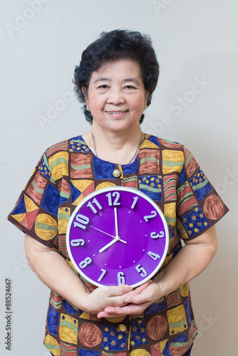 Asian senior woman holding purple clock in studio shot, specialt photo