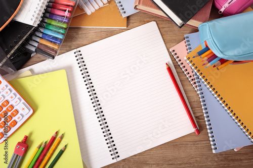 Busy student desk in college or school with blank open notebook pencils and equipment studying homework photo with space for copy text photo