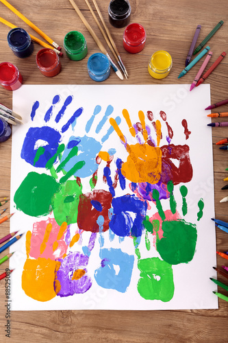 Child handprints or hand prints and art equipment on a school desk with paint arts and crafts equipment photo