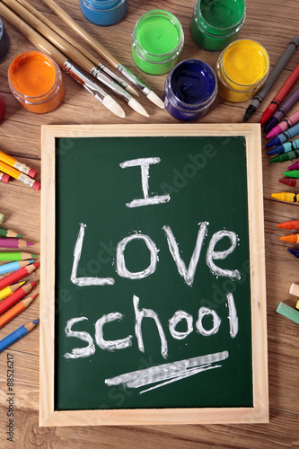  I love school writing written on a small chalk blackboard on a student desk surrounded by pencils and crayons photo