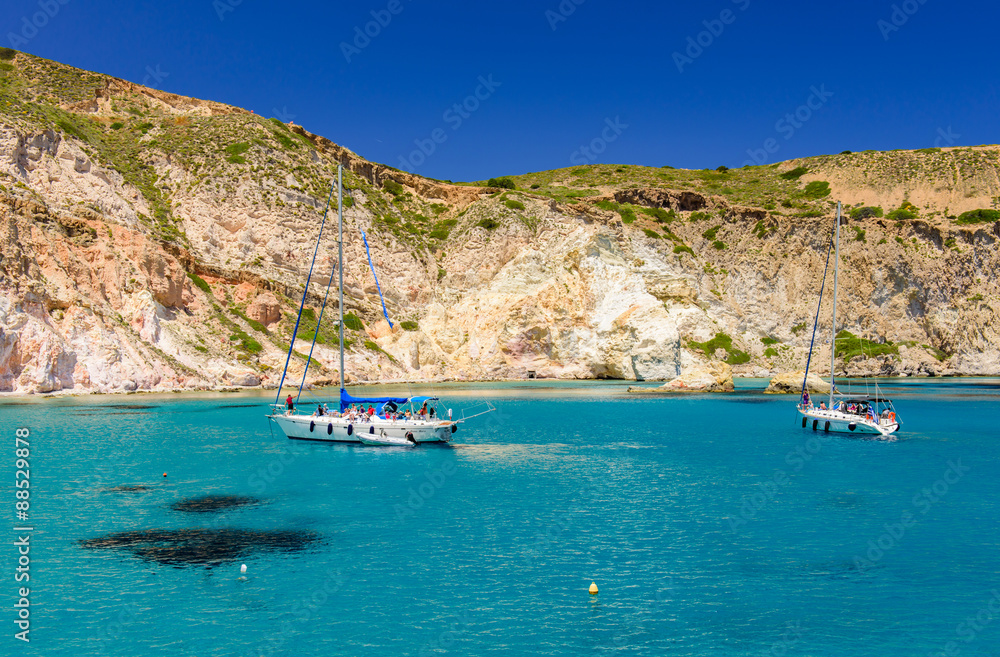 snow-White yacht in the blue waters of the picturesque Bay, Mandrakia village, Milos island, Cyclades, Greece.