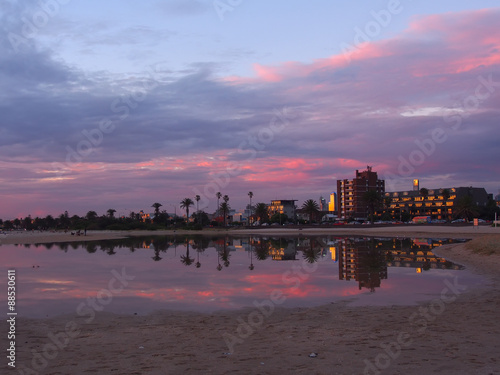 buildings & sunset reflected in water. St Kilda beach, Melbourne, Australia.