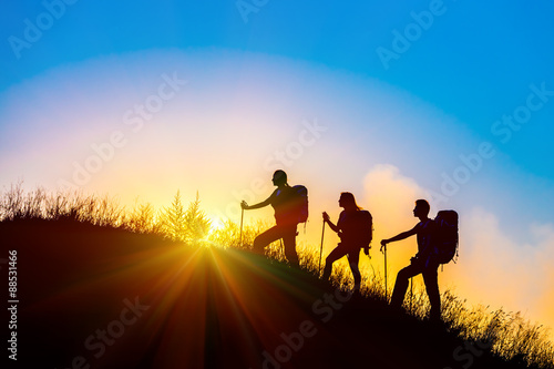 People meeting sunrise team building session Group of people silhouettes walking toward mountain summit backpacks hiking gear meeting uprising sun blue sky background