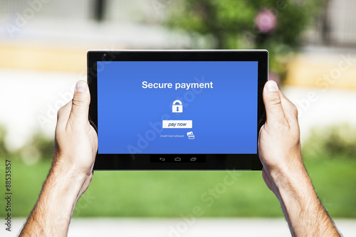 Hands holding tablet. Secure payment on the screen. Blue and white interface background.