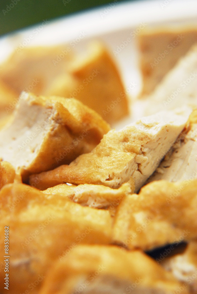 Indonesian fried tofu on white plate - extreme closeup view. Indonesian fried tofu on white plate - extreme closeup view.