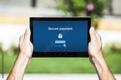 Hands holding tablet. Secure payment on the screen. Blue interface background.