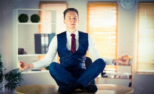 Calm businessman meditating in lotus pose