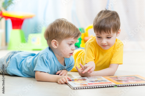 Kids looking at book in playschool or nursery