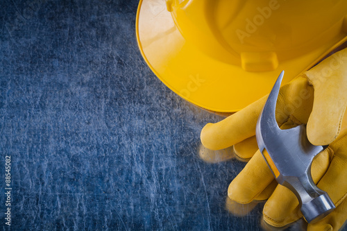 Pair of protective gloves hard hat and claw hammer on scratched 