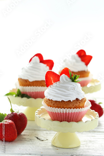 Tasty cupcake with strawberry on cake stand on white wooden back