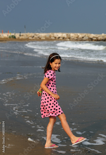 Little Girl with pink dress with small black hearts of the beach