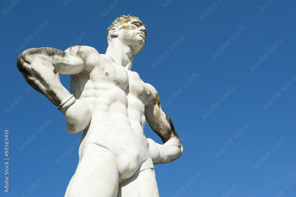 Ancient marble statue of muscular athlete boxer with sculpted body against bright blue sky Ancient marble statue of muscular athlete boxer with sculpted body against bright blue sky