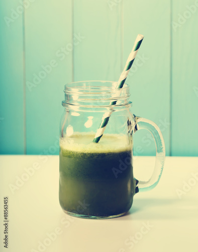 Green smoothie in masons jar with paper straw photo