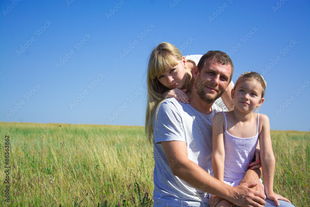 Young happy family in a field of a mom dad daughter