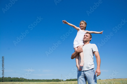 Happy father with his little daughter in his arms in the field